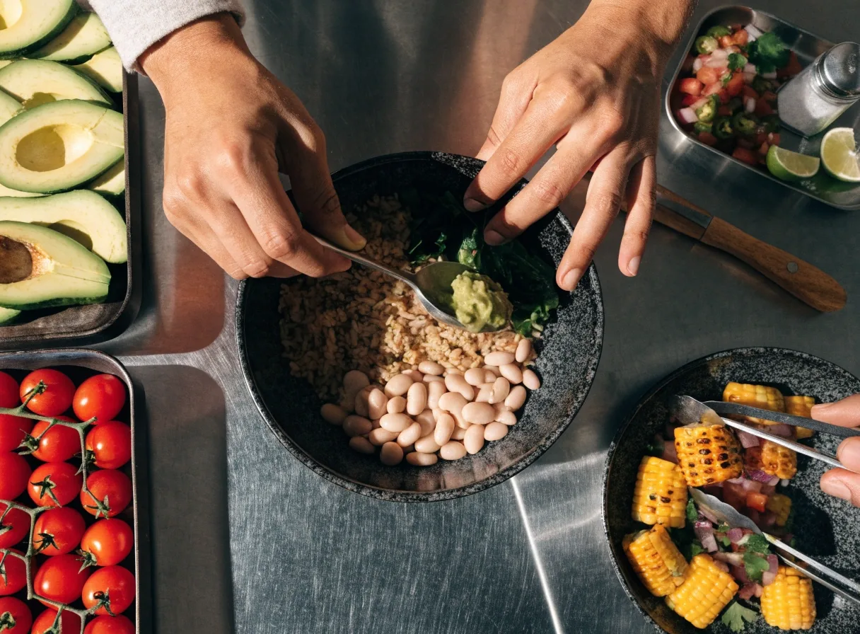 Hands assembling a burrito bowl with fresh fillings